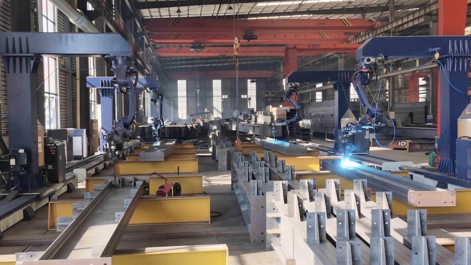 Robotic welding stations working on structural-steel beams in a production facility